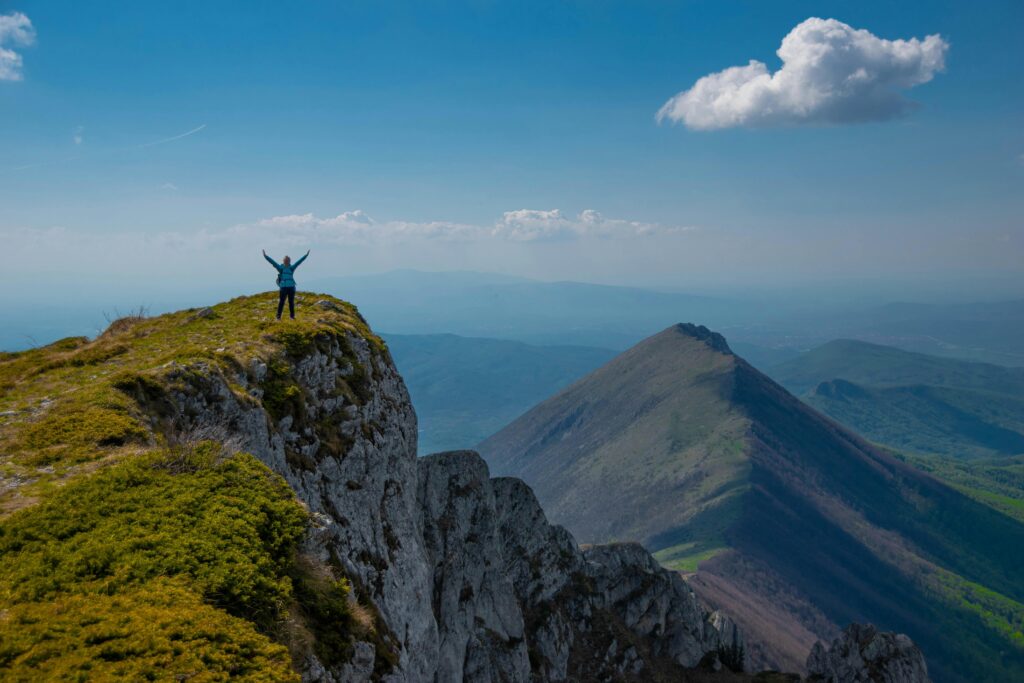 A person celebrating victory atop a mountain peak in Serbia with breathtaking views.