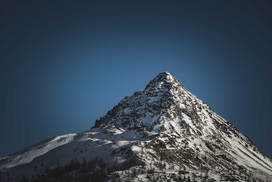 Majestic snow-covered mountain peak rising beneath a clear blue sky, showcasing natural beauty.