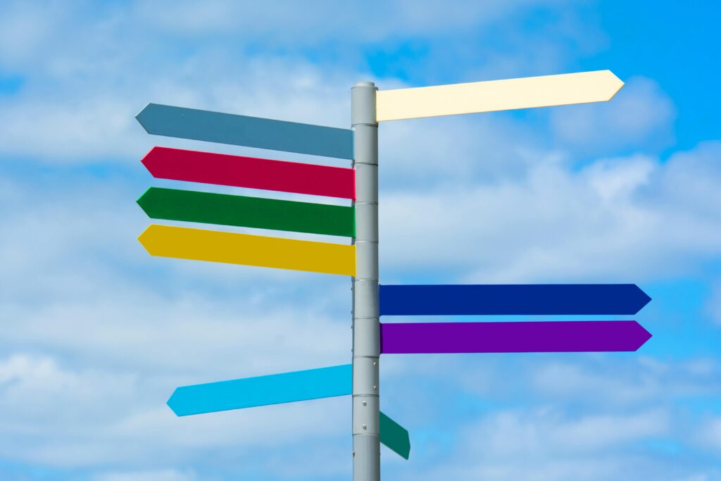 Multicolored directional signpost against a vibrant blue sky, offering guidance.